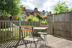 A wooden deck with two wooden benches and a table, surrounded by a wooden fence.