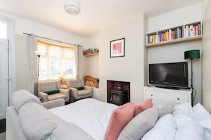 A bedroom with a bed, a television, a fireplace, a bookshelf, and a window with curtains.