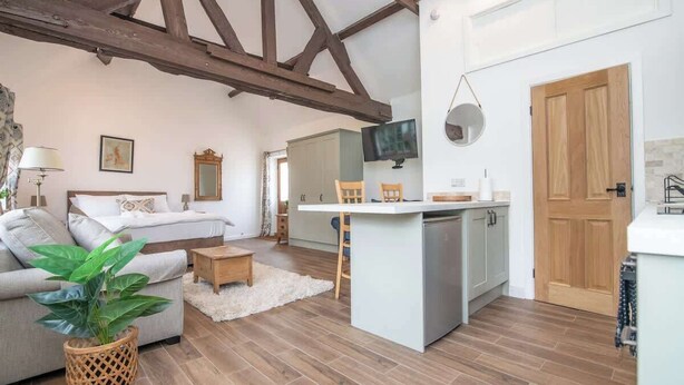 A cozy room with a bed, a sofa, a dining area, and a kitchen. - Charming Warwickshire Studio (Wootton Wawen)