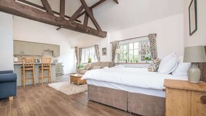 A bedroom with a bed, wooden beams, a window, a desk, and a chair. - Charming Warwickshire Studio (Wootton Wawen)