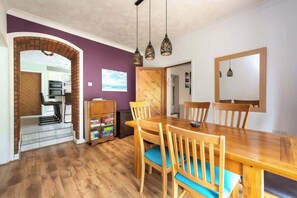 A dining area with a wooden table and chairs, a brick archway, a bookshelf, and a view of the kitchen. - Spacious 5BR Home in Redditch (Redditch)