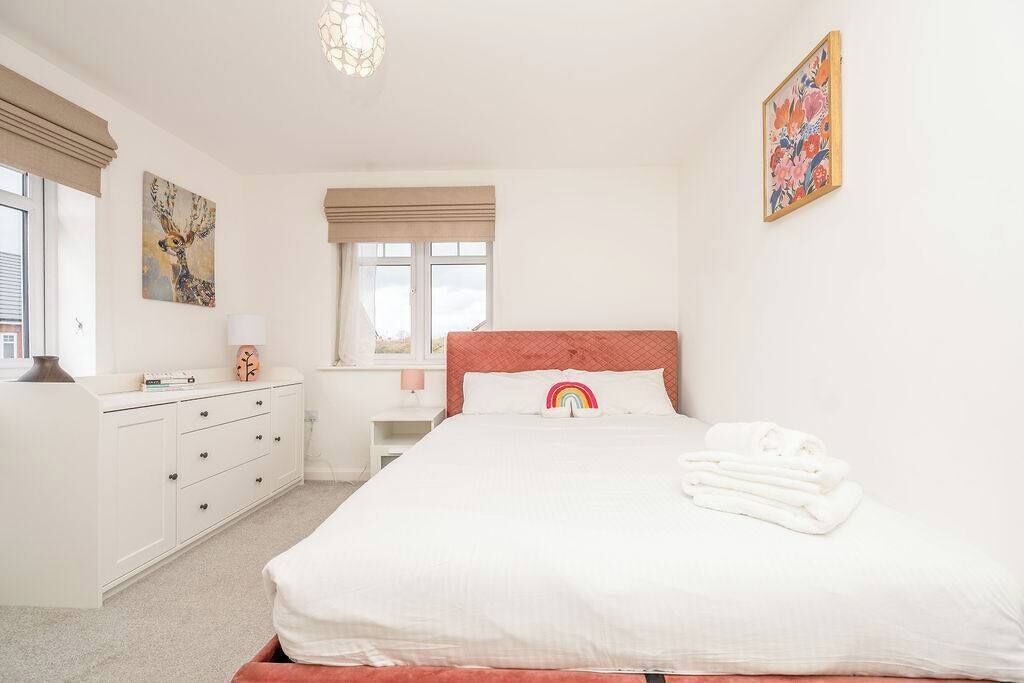 Une chambre à coucher avec un lit, une commode, une fenêtre et des œuvres d’art accrochées aux murs.