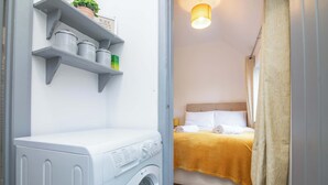 Un'area lavanderia con una lavatrice ed scaffali contenenti utensili da cucina.