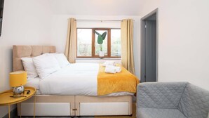 Una camera da letto ordinata con un letto, un comodino, una lampada e vista sull'esterno.