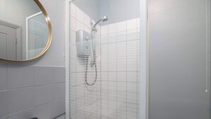 Un bagno con doccia, lavandino e specchio.