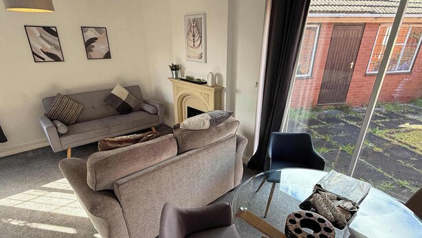 A living room with a grey sofa, a glass coffee table, and a fireplace.