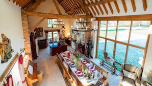 Une salle à manger spacieuse avec une longue table, des poutres en bois au plafond et une vue sur l’eau.