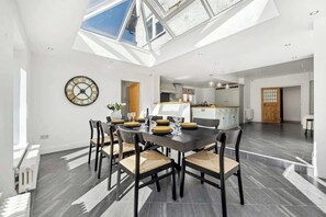 A dining area with a high ceiling, skylight, and a view of the kitchen. - Windsor Manor: Luxury 5-bed Retreat in Solihull (Solihull)