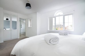 A white room with a bed, a window, and a wardrobe. - 5 BD - Large House Oadby (Leicester)