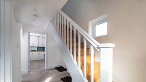 A staircase with white railings and wooden steps leading to a second floor. - Compton House - 4 Bed (Cheltenham)