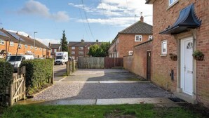 A residential street with houses, a gated driveway, and a white van parked on the side. - Compton House - 4 Bed (Cheltenham)