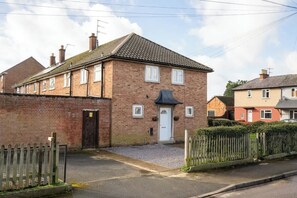 A two-story brick house with a front door, windows, and a small front yard.
