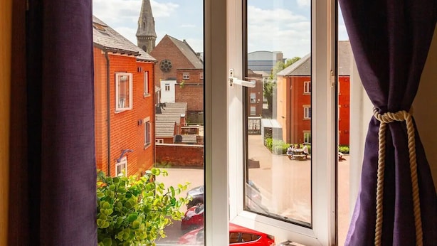 A window with a view of a residential area, including a church steeple and houses. - For Students Only - Park Court in Lincoln - Campus Accommodation (Lincoln)