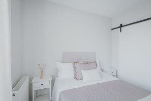 Un dormitorio minimalista con cama, mesita de noche y radiador.
