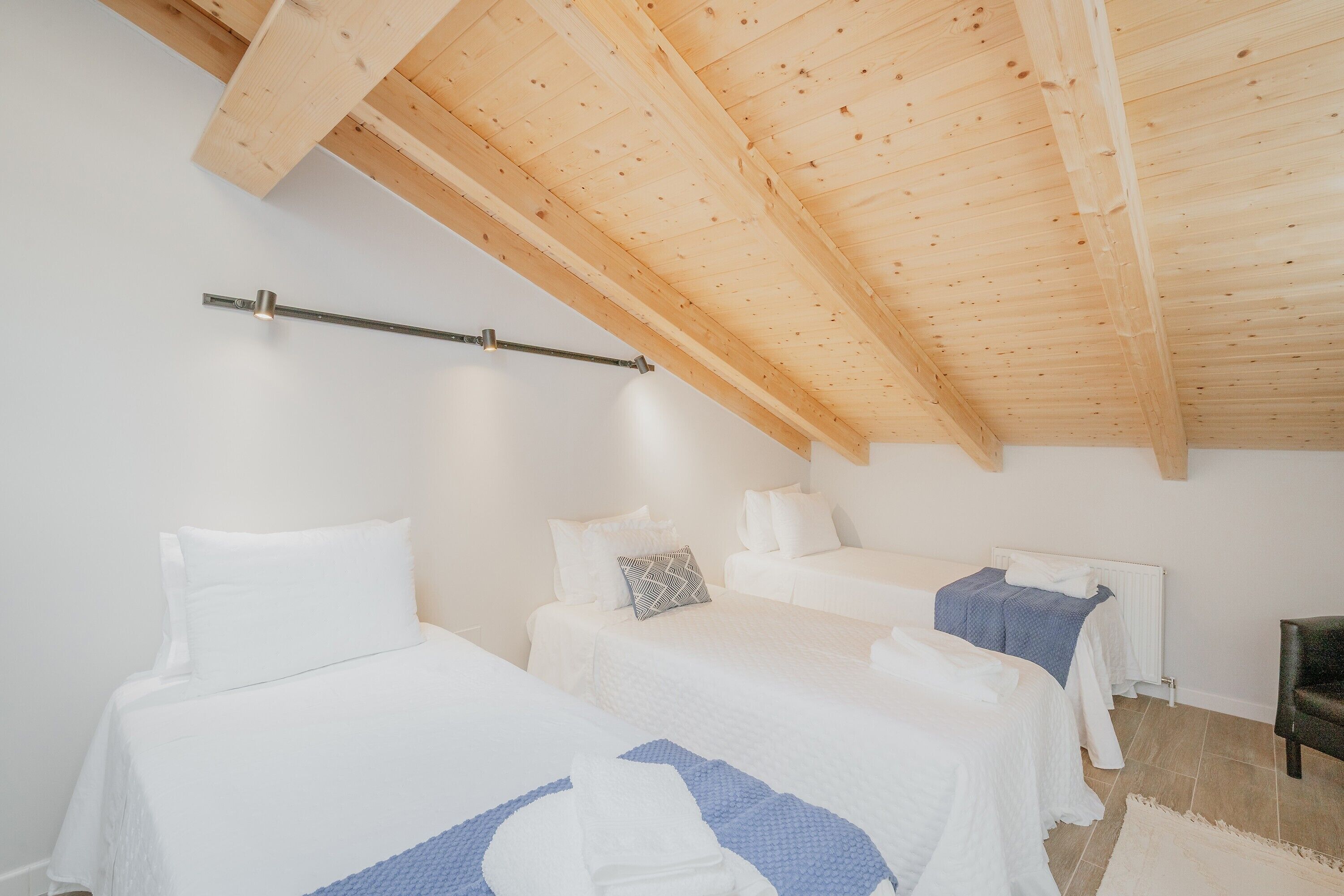 Ein Schlafzimmer mit zwei Betten, einer Holzbalkendecke, weißen Wänden und einer Heizung.