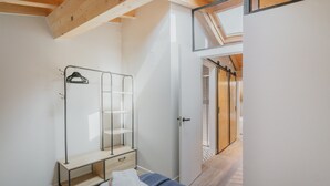 Quarto com cama, guarda-roupa, estante e claraboia.