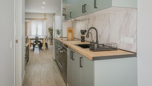 Uma cozinha moderna com painel de parede em mármore, bancada de madeira e eletrodomésticos de aço inoxidável.