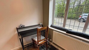 Et hjørneværelse med radiator, et vindue med udsigt til det fri, og en lille træstol.