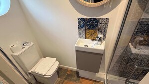 Et badeværelse med toilet, håndvask og bruseområde.