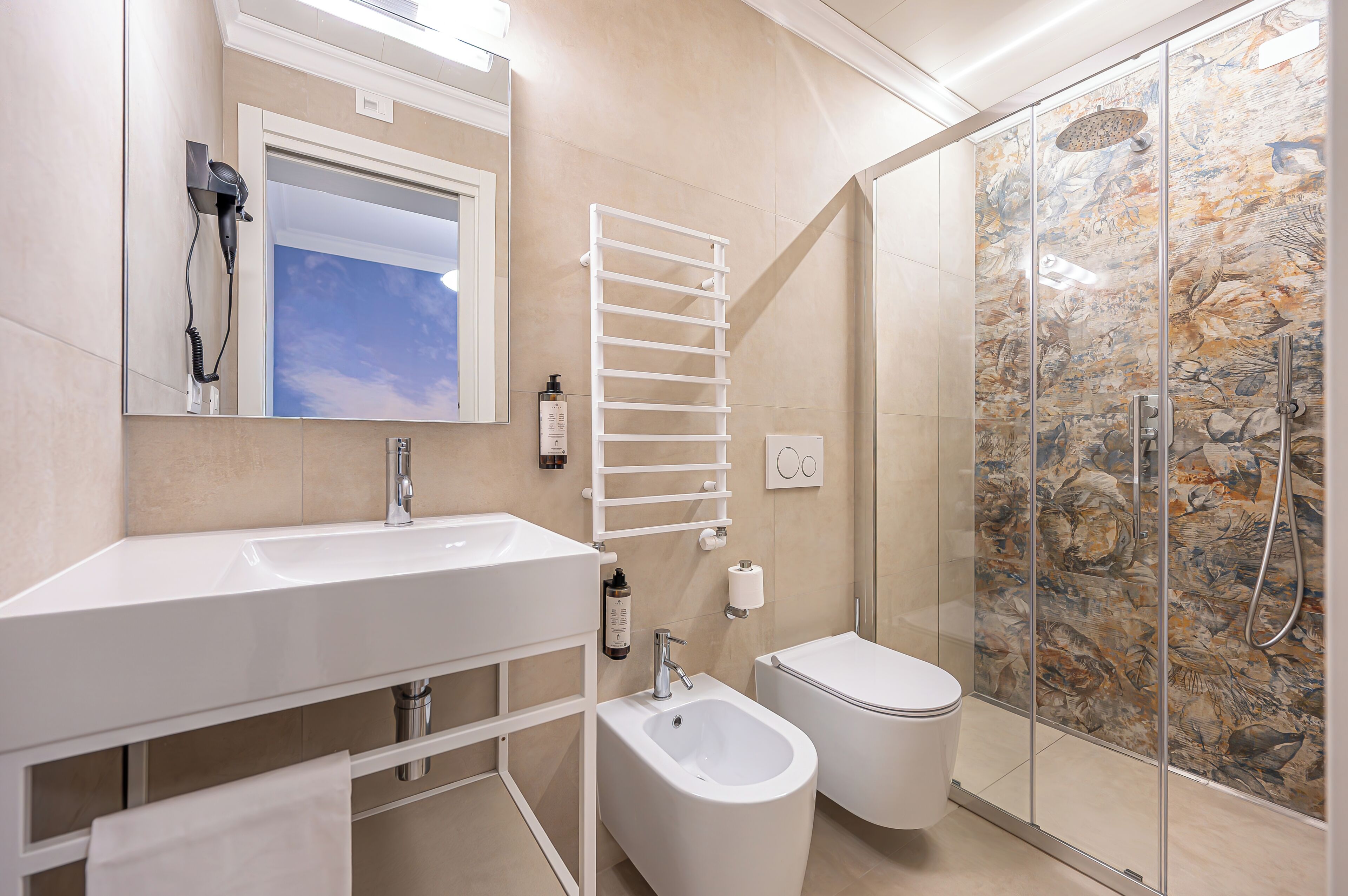 Une salle de bain équipée d’un lavabo, d’un bidet, de toilettes et d’une douche avec un mur en pierre.