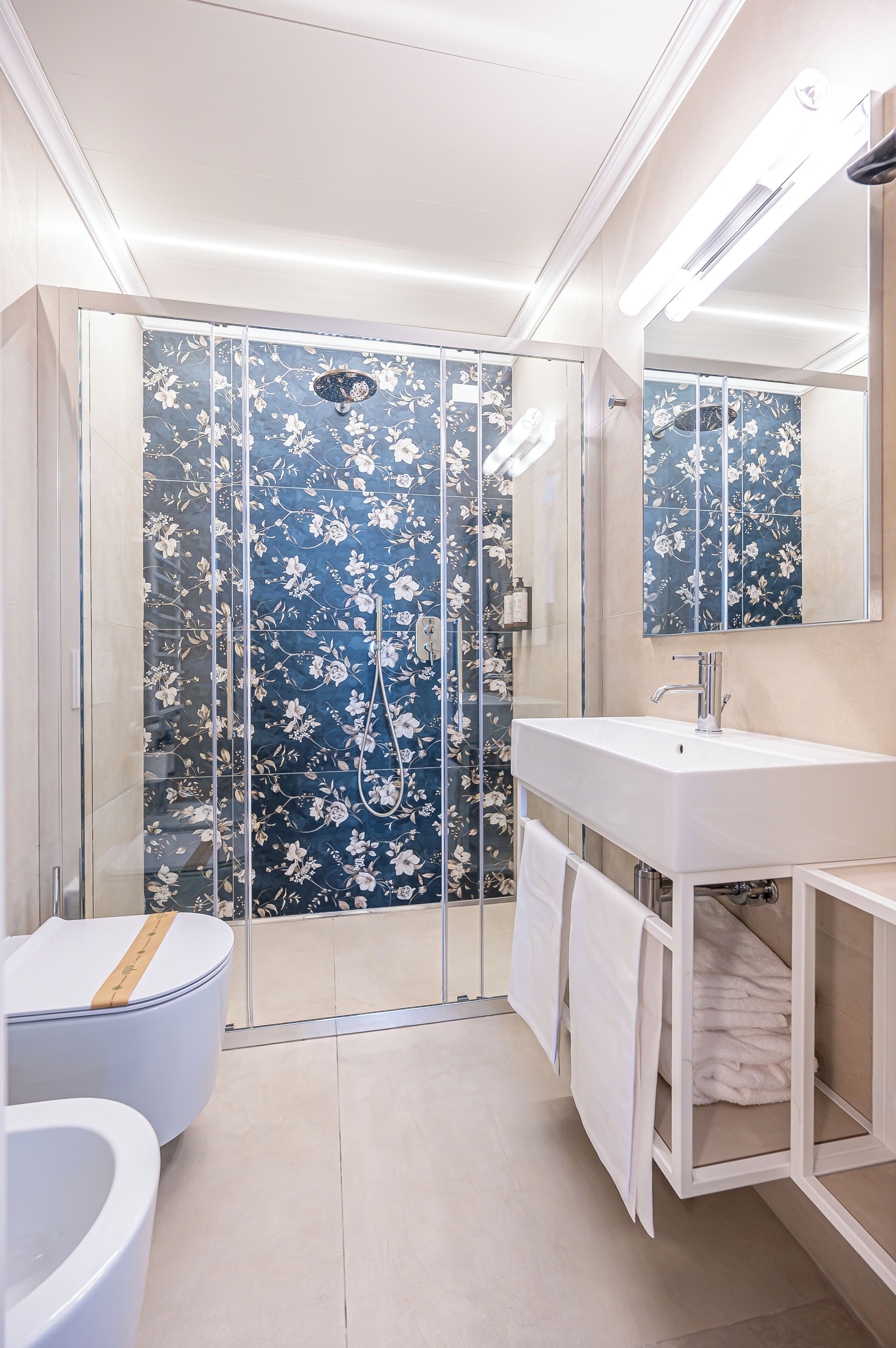 A bathroom with a glass shower enclosure, a white sink, and a toilet.