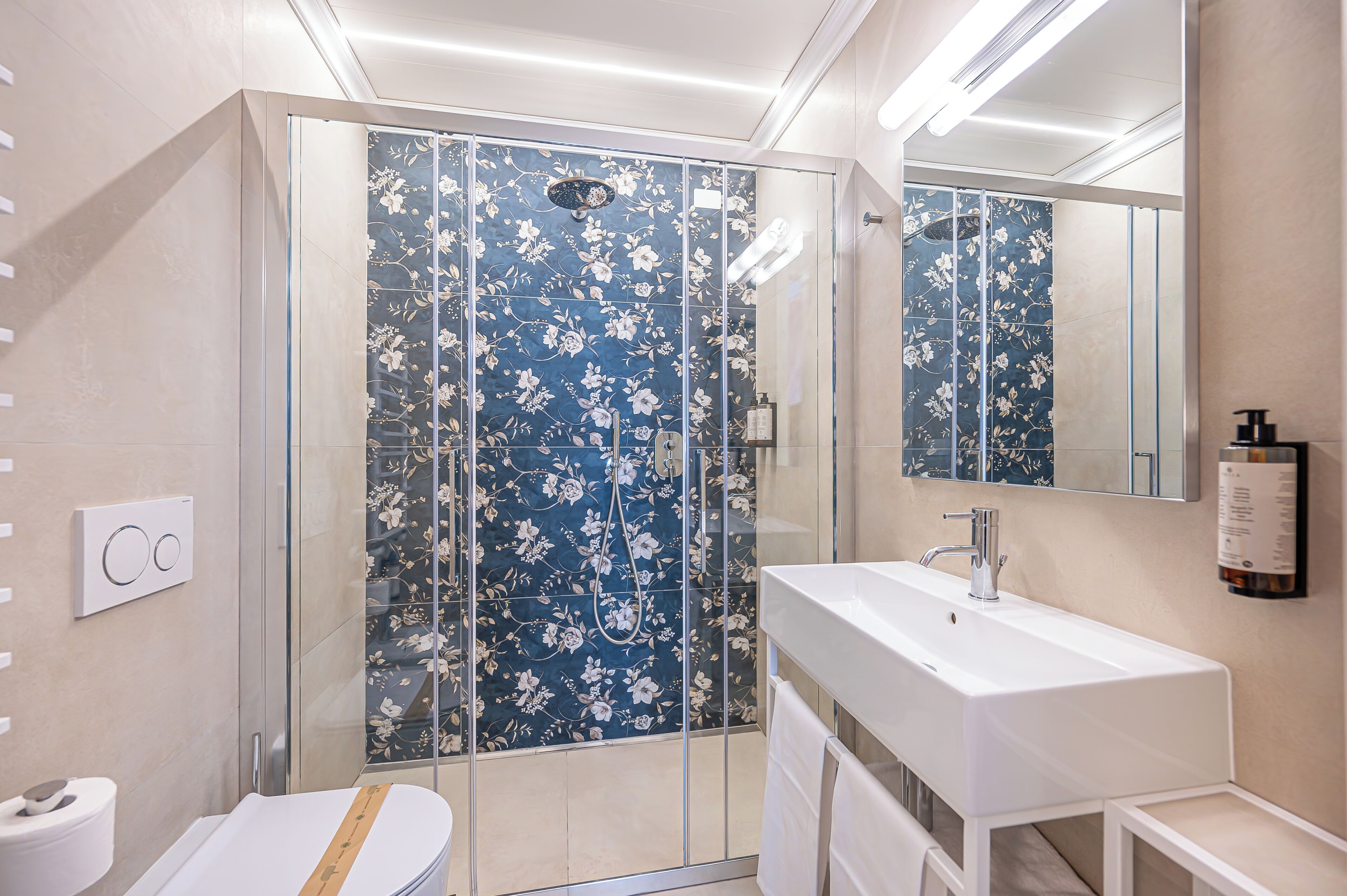 Une salle de bain moderne avec une douche à parois de verre, un lavabo blanc et un miroir.