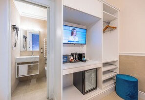 Casa de banho moderna com toucador, porta-toalhas e televisão exibindo um canal de notícias.