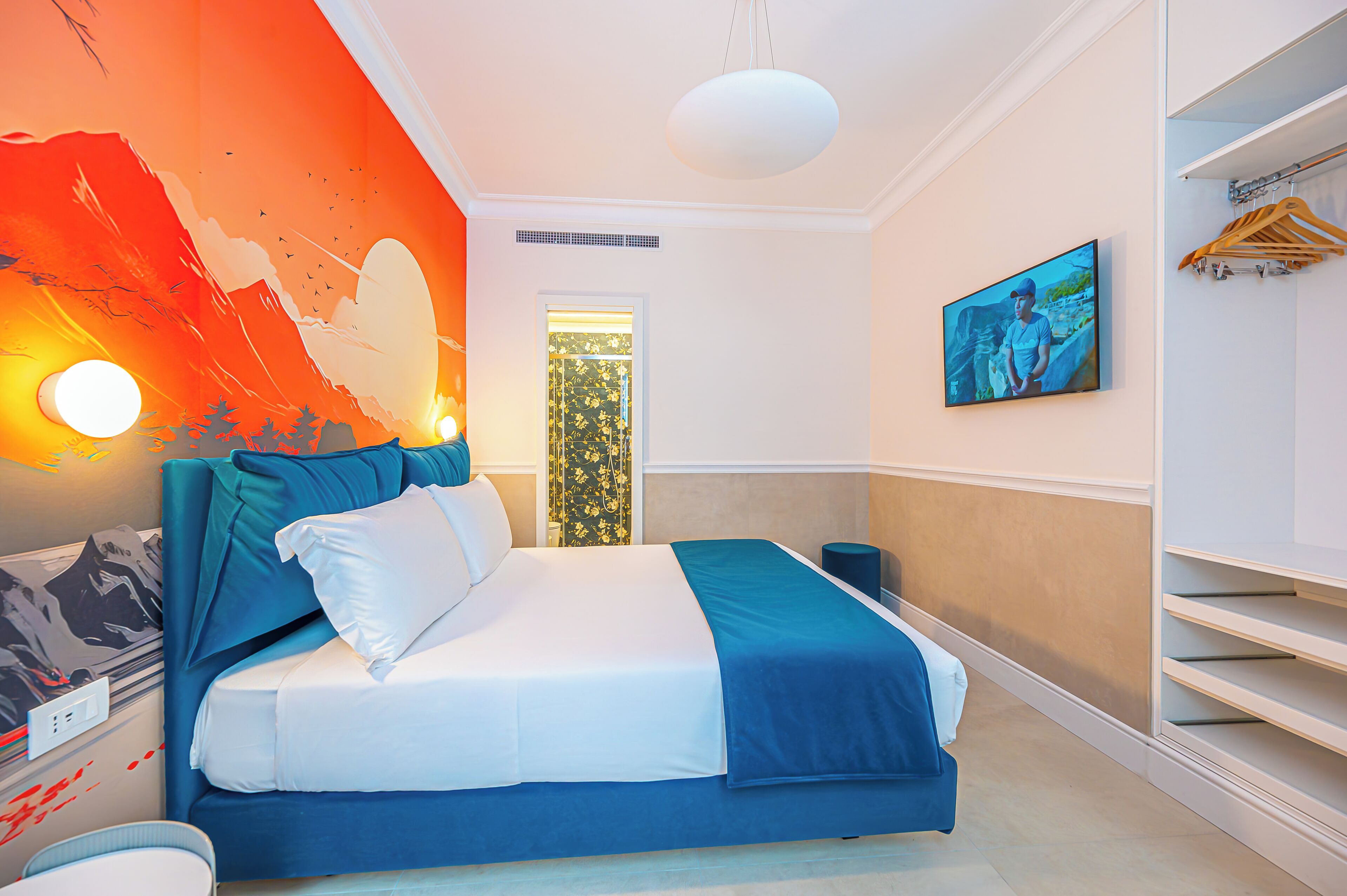 A bedroom with a bed, a wall mural, a painting, and a window.