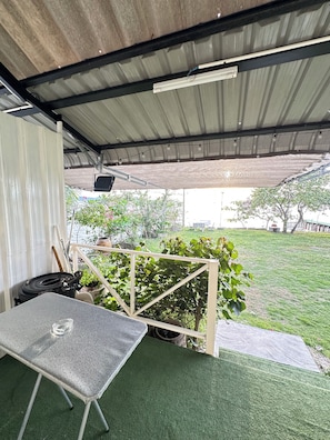 A covered outdoor area with a table, chairs, and a view of a grassy yard. - Summer Sunshine Resort Songkhla (Songkhla)
