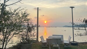 A lakeside view with a sunset, chairs, and a lamp post. - Summer Sunshine Resort Songkhla (Songkhla)
