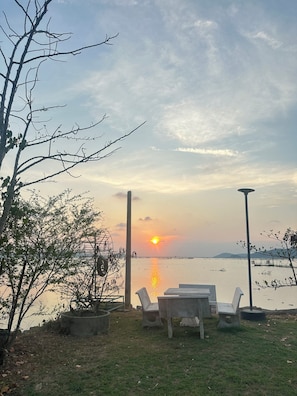 A lakeside view with a sunset, chairs, and a lamp post. - Summer Sunshine Resort Songkhla (Songkhla)