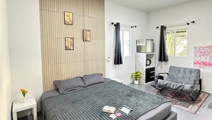 A modern bedroom with a large bed, a small bedside table, a dresser, a chair, and a window with curtains. - Summer Sunshine Resort Songkhla (Songkhla)