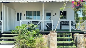 A white building with a porch, steps leading to the entrance, and a small garden area with plants and a bench. - Summer Sunshine Resort Songkhla (Songkhla)