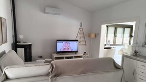 Una sala de estar con un sofá, una televisión, una escalera y una ventana.
