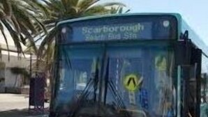 En turkis bus med 'Scarborough' og 'Bus 5' på forsiden, parkeret på en gade med palmer i baggrunden.