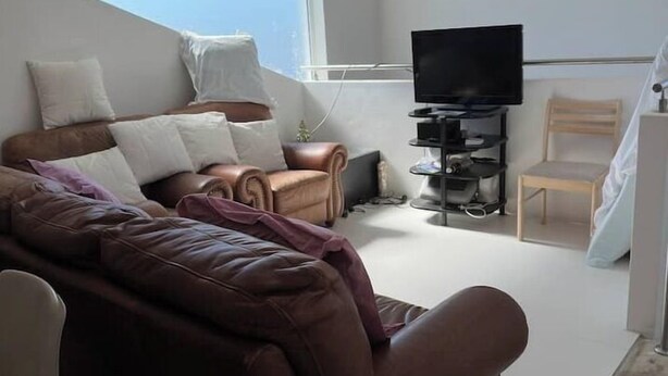 En moderne stue med en brun sofa, et fjernsyn og et lille bord.
