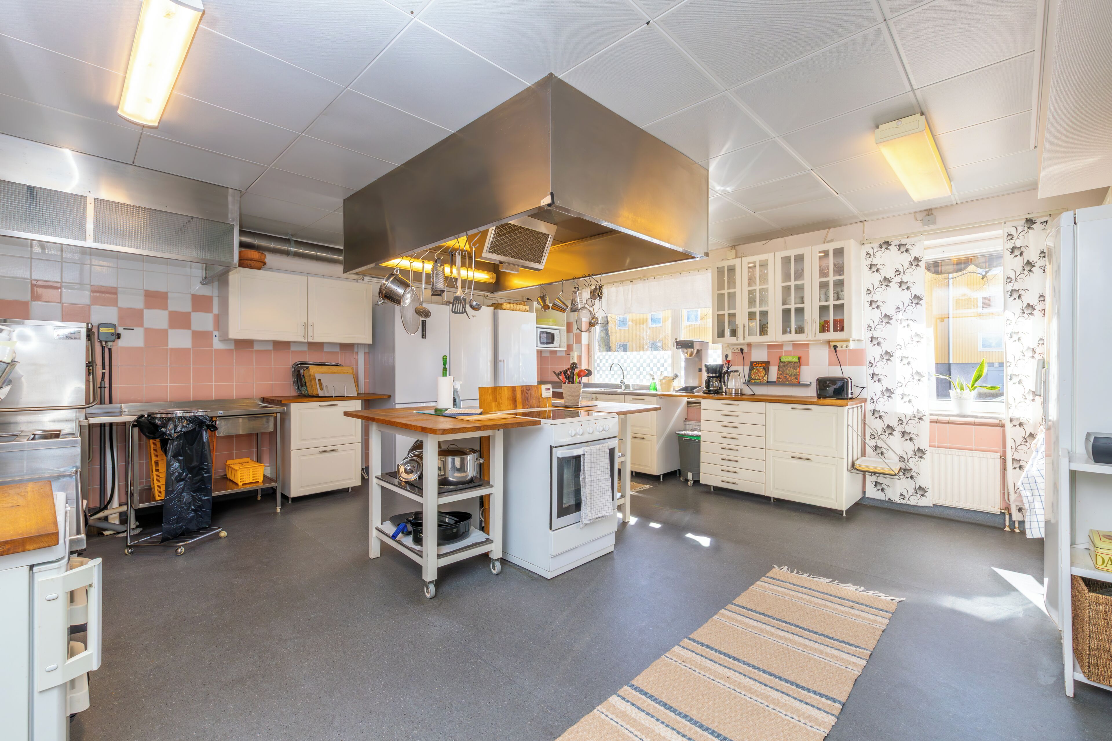 Una cocina moderna con una isla central, muebles blancos y una campana extractora.