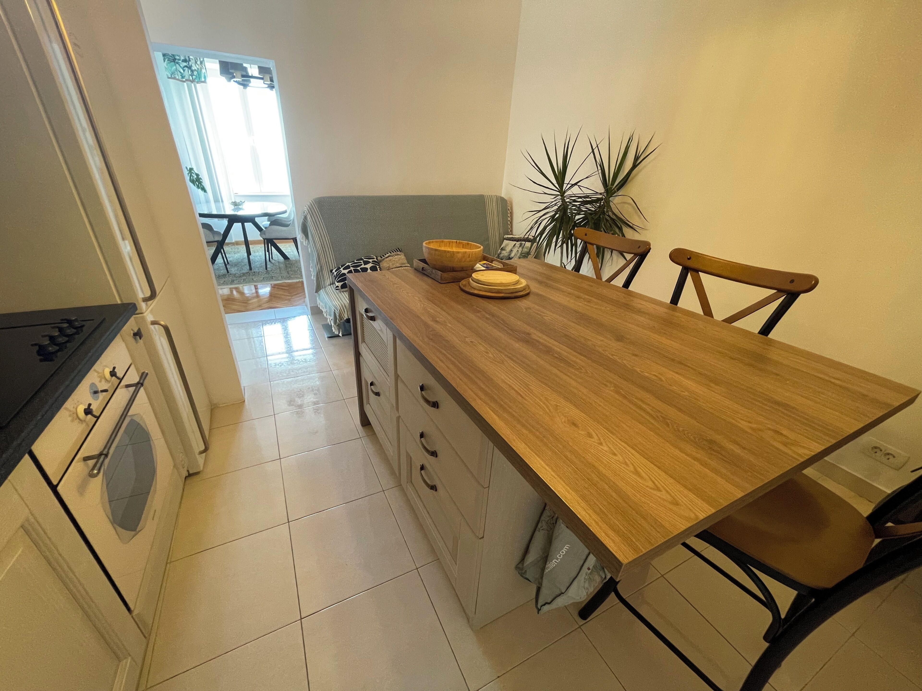 A kitchen with a wooden countertop, a stove, and a dining area with chairs and a table.