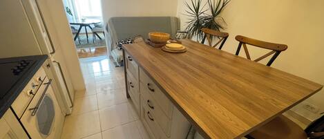 A kitchen with a wooden countertop, a stove, and a dining area with chairs and a table.