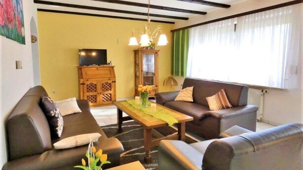 Een woonkamer met twee banken, een salontafel, een televisie en een kast.
