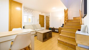 Ein modernes Wohnzimmer mit einer Holztreppe, einem Essbereich mit Tisch und Stühlen sowie einem Sofa.