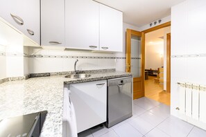 A kitchen with white cabinets, a stainless steel sink, a dishwasher, and a tiled backsplash. - (PRA10) 2 bedroom and 2 bathroom apartment in the center of Madrid (Madrid)