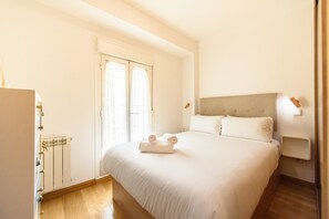 A hotel room with a bed, a radiator, a window with curtains, and a bedside table. - (PRA10) 2 bedroom and 2 bathroom apartment in the center of Madrid (Madrid)