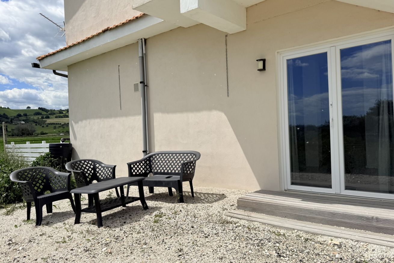 A patio with outdoor furniture, a building with a tiled roof, and a sliding glass door.