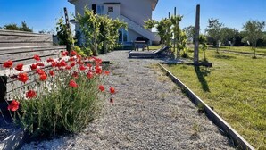 A house with a gravel path, a wooden bench, and red flowers. - PP11 - Potenza Picena, new three-room apartment with pool and air conditioning (Potenza Picena)