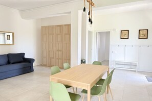 Ein modernes Wohnzimmer mit einer Couch, einem Esstisch mit Stühlen, einem Holzschrank und einer Lampe.