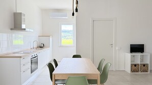 A modern kitchen with a dining area, white cabinetry, a built-in oven, and a window with a view. - PP11 - Potenza Picena, new three-room apartment with pool and air conditioning (Potenza Picena)