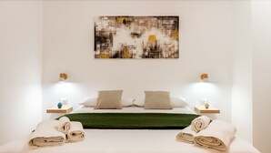 A neatly made bed with two pillows, a green throw, and rolled towels on either side. - 'Il Cortile Holiday House - Dimora Maiolica' Apartment with Wi-Fi and Air Conditioning (Caccamo)