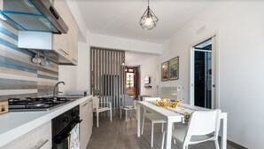 Cozinha moderna com fogão a gás, forno e área de jantar com mesa e cadeiras.