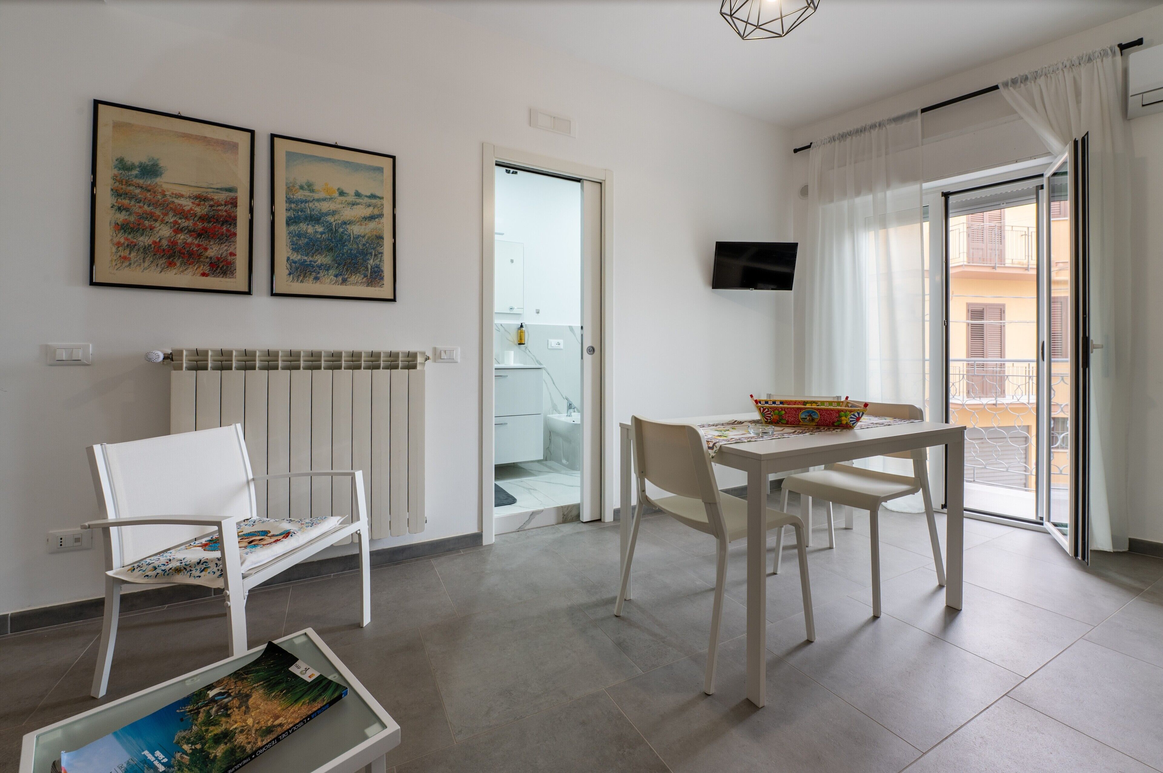 Una sala de estar moderna con una mesa de comedor, sillas, un radiador y dos cuadros enmarcados.